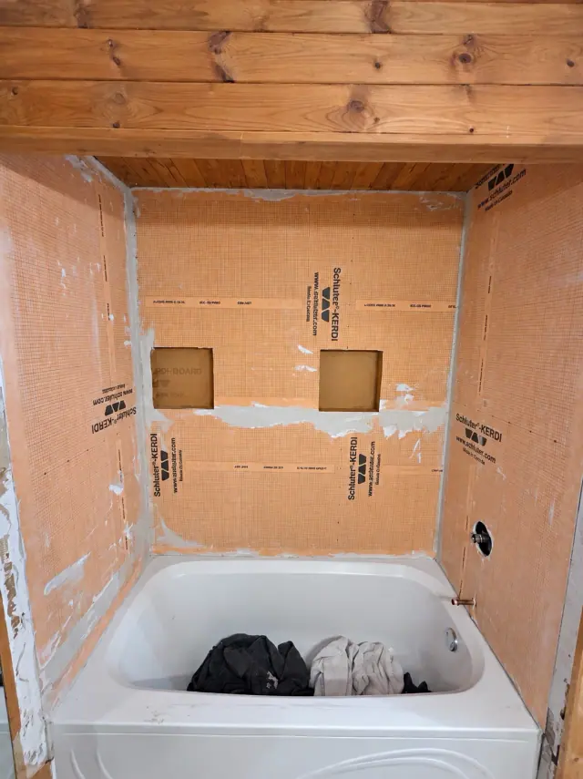 Schluter waterproofing board and two recessed niches around a bathtub before tiling